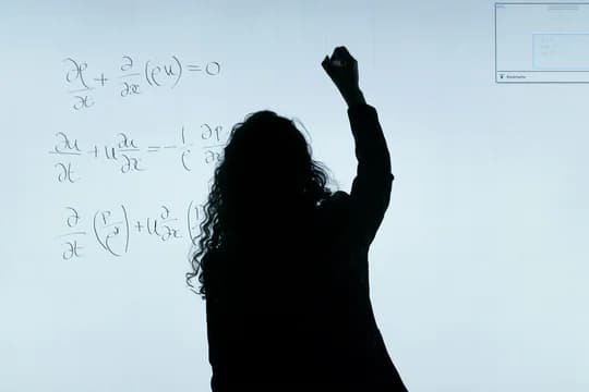 Woman writing math equation on whiteboard